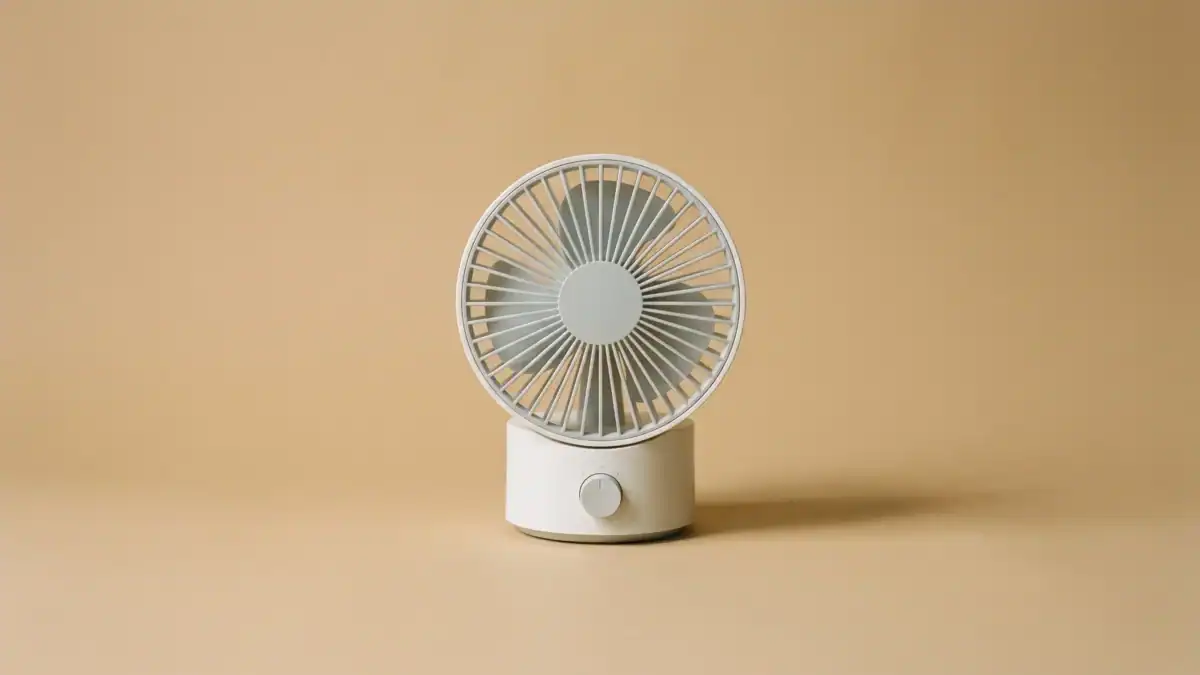 Ventilador de sobremesa apagado sobre fondo beige, bodegón editorial — cuesta de septiembre — unente