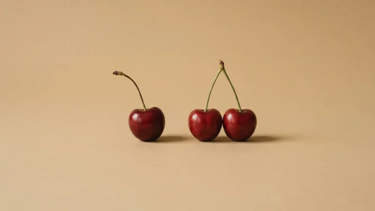 Cereza suelta junto a dos cerezas unidas por el rabo, bodegón editorial — declaración conjunta o individual — unente