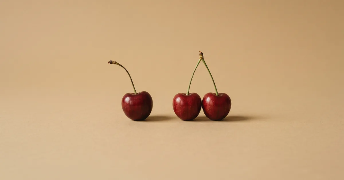 Cereza suelta junto a dos cerezas unidas por el rabo, bodegón editorial — declaración conjunta o individual — unente